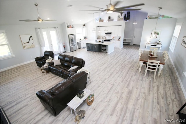 living room with high vaulted ceiling, light wood-style flooring, baseboards, and a ceiling fan