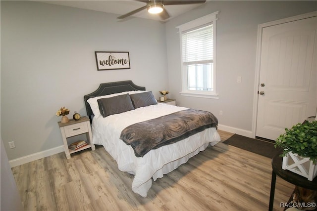 bedroom featuring light wood-style flooring, a ceiling fan, and baseboards