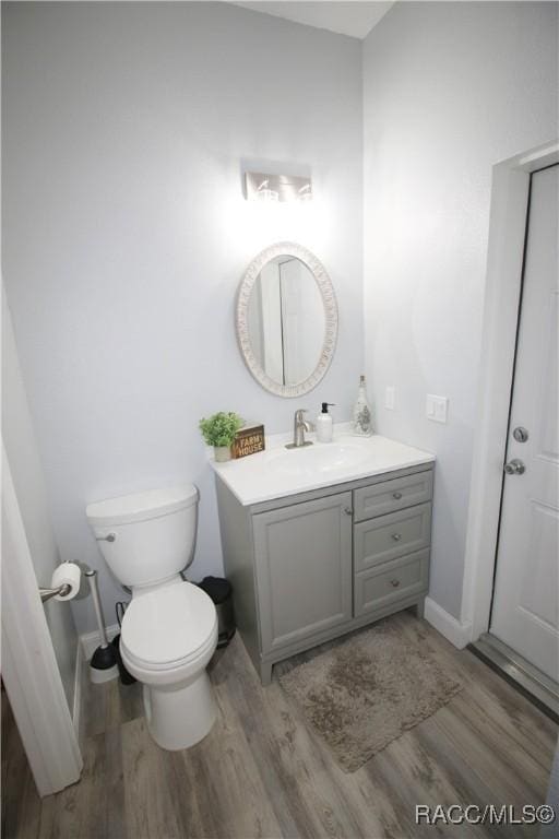 half bath featuring vanity, toilet, and wood finished floors