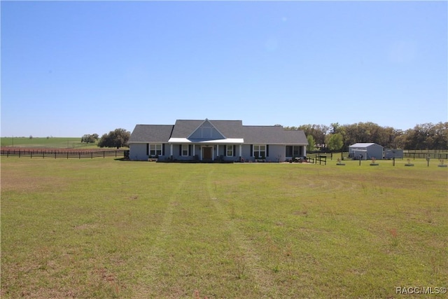 view of front facade featuring a rural view, a front yard, and fence