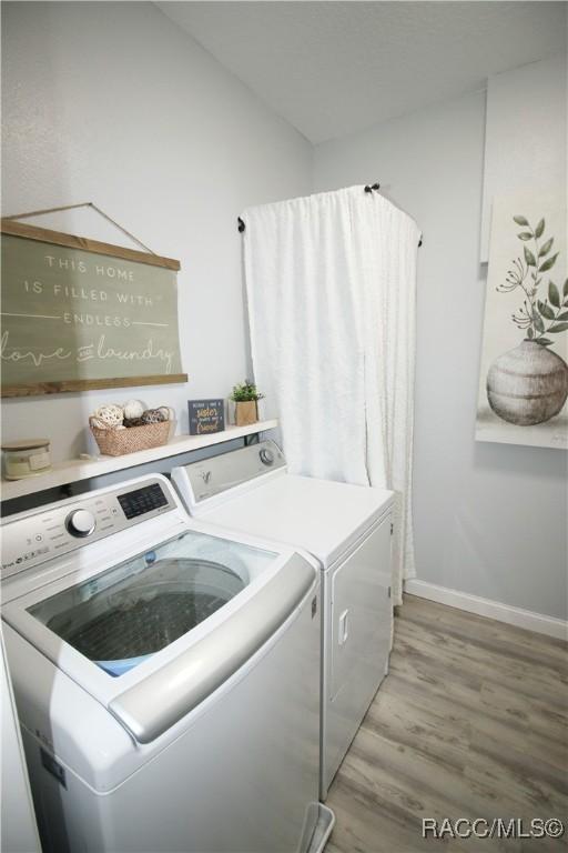 laundry area featuring laundry area, baseboards, light wood finished floors, and washing machine and clothes dryer