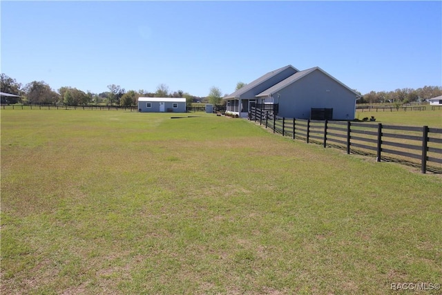 view of yard featuring an outbuilding, a rural view, and fence