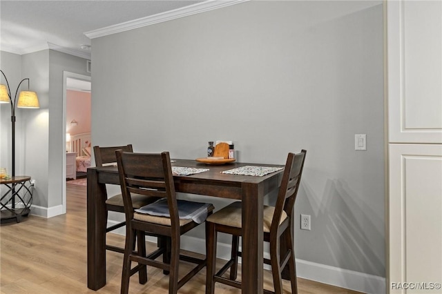 dining area featuring ornamental molding and light hardwood / wood-style floors