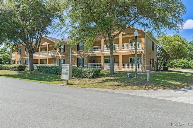 view of front of home featuring a front lawn and a balcony