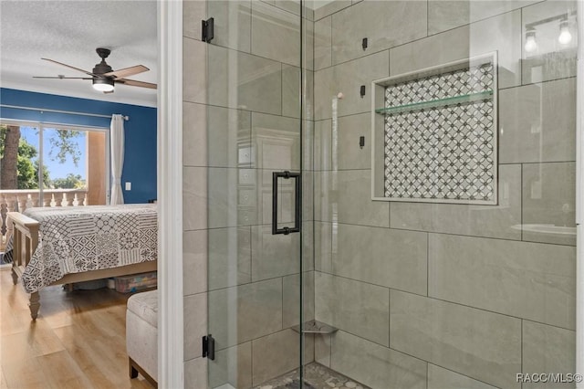 bathroom featuring hardwood / wood-style flooring, a shower with door, a textured ceiling, and ceiling fan