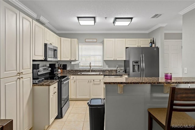 kitchen featuring sink, light tile patterned floors, ornamental molding, a kitchen breakfast bar, and stainless steel appliances