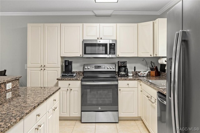 kitchen with crown molding, appliances with stainless steel finishes, light tile patterned floors, and dark stone countertops