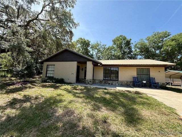 single story home with metal roof, a front lawn, stone siding, and stucco siding