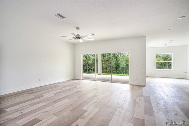 empty room with ceiling fan, light hardwood / wood-style floors, and a textured ceiling