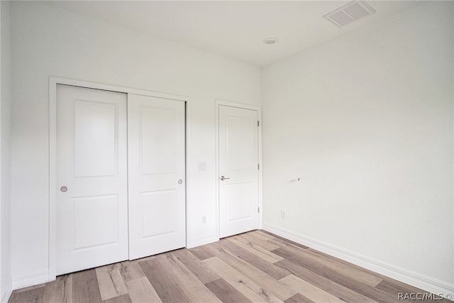 unfurnished bedroom with a closet and light wood-type flooring