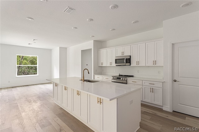 kitchen featuring sink, white cabinetry, stainless steel appliances, and a kitchen island with sink