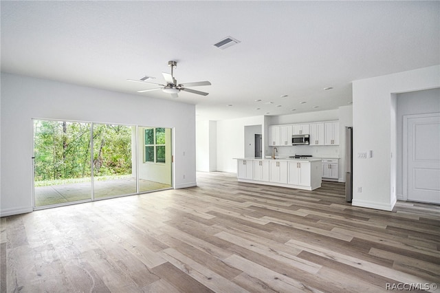 unfurnished living room with light hardwood / wood-style floors, ceiling fan, and sink