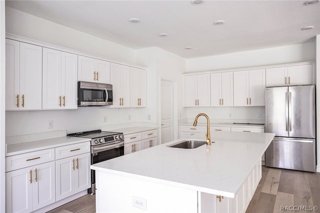 kitchen with stainless steel appliances, light hardwood / wood-style flooring, a kitchen island with sink, and sink