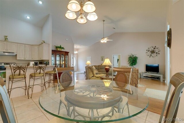 dining area featuring ceiling fan with notable chandelier, high vaulted ceiling, and light tile patterned floors