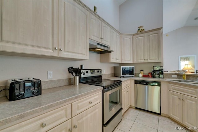 kitchen with vaulted ceiling, light brown cabinetry, sink, light tile patterned floors, and stainless steel appliances