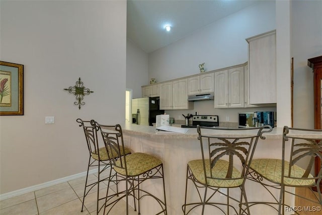 kitchen with a breakfast bar, high vaulted ceiling, stainless steel appliances, light tile patterned flooring, and kitchen peninsula