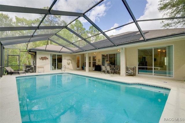 view of pool with a patio area and glass enclosure