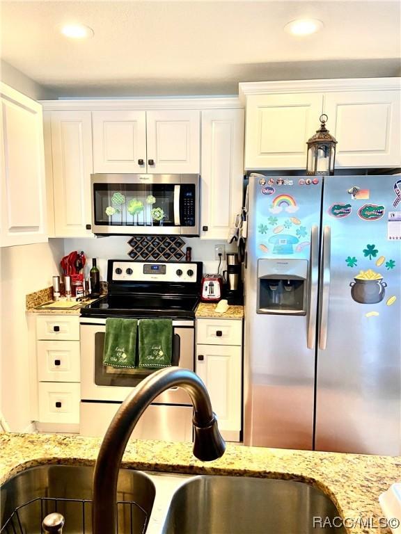 kitchen featuring light stone countertops, sink, white cabinetry, and appliances with stainless steel finishes