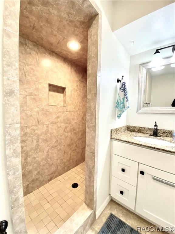 bathroom with a tile shower, tile patterned floors, and vanity