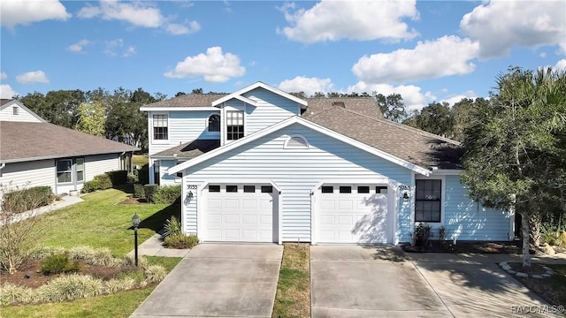 traditional-style house featuring driveway, a shingled roof, a garage, and a front lawn