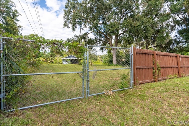 view of gate with a lawn