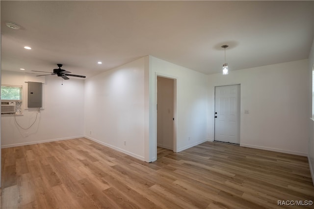 unfurnished room with electric panel, ceiling fan, light hardwood / wood-style flooring, and cooling unit