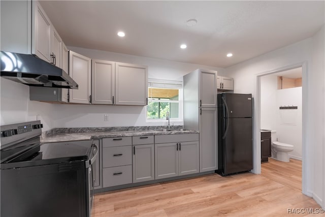 kitchen with gray cabinetry, black refrigerator, electric stove, and light hardwood / wood-style flooring