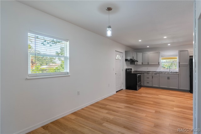 kitchen with pendant lighting, black range with electric stovetop, sink, light hardwood / wood-style flooring, and gray cabinets