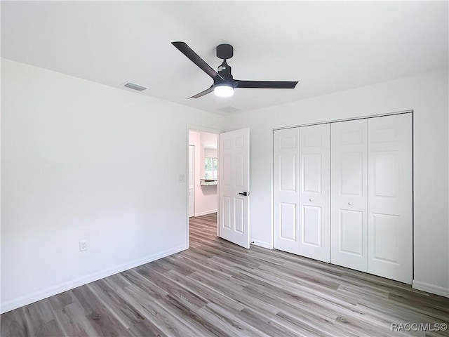 unfurnished bedroom with light hardwood / wood-style flooring, ceiling fan, and a closet