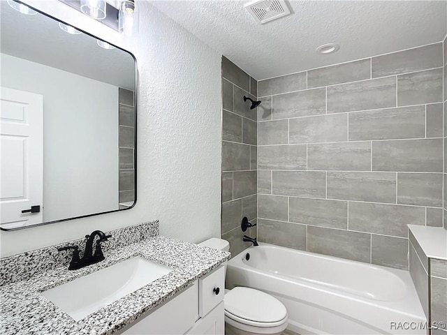 full bathroom with tiled shower / bath, vanity, toilet, and a textured ceiling