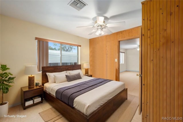 bedroom featuring wood walls, visible vents, a ceiling fan, and baseboards