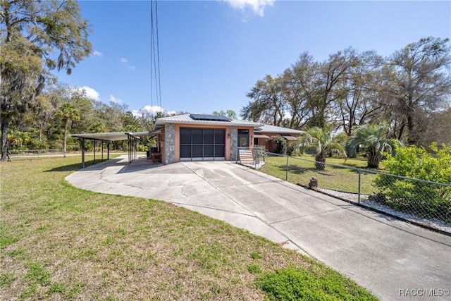 ranch-style home featuring roof mounted solar panels, a front lawn, an attached garage, and concrete driveway