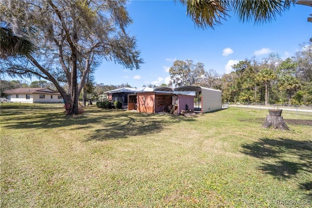 view of yard with fence, a carport, and an outbuilding