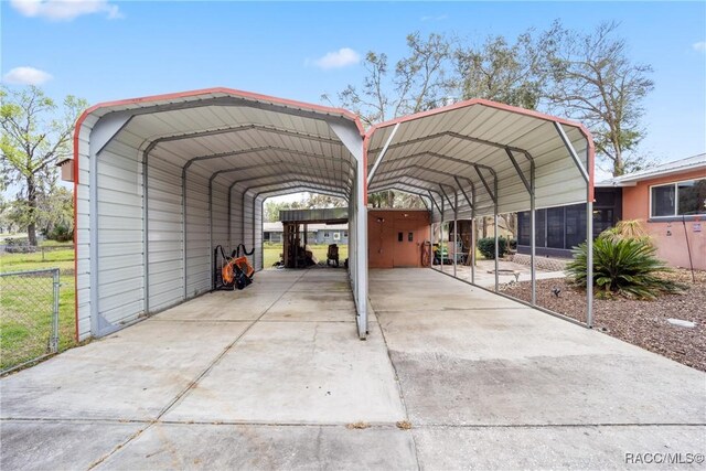 view of car parking featuring concrete driveway, a carport, and fence