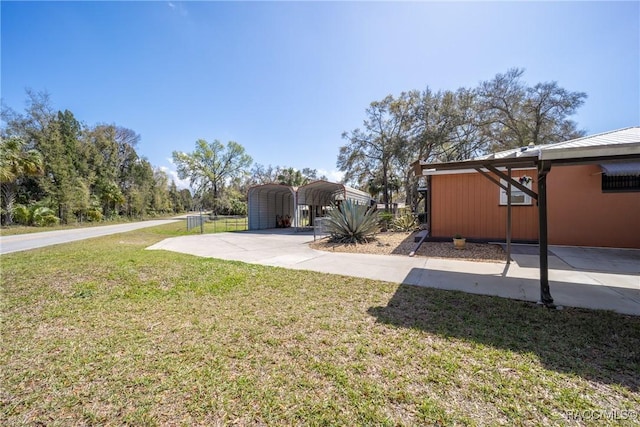 view of yard featuring driveway, a detached carport, and fence