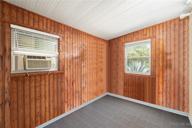 unfurnished room featuring wood walls, cooling unit, and baseboards
