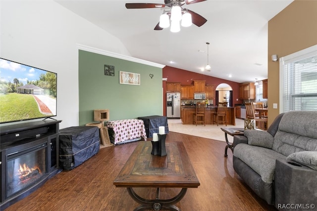 living room with ornamental molding, hardwood / wood-style flooring, ceiling fan, and lofted ceiling