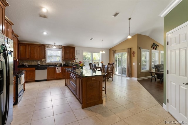 kitchen featuring hanging light fixtures, light tile patterned floors, stainless steel dishwasher, lofted ceiling, and a kitchen island