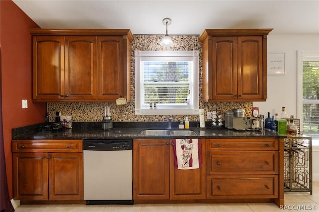 kitchen featuring dark stone countertops, plenty of natural light, stainless steel dishwasher, and sink