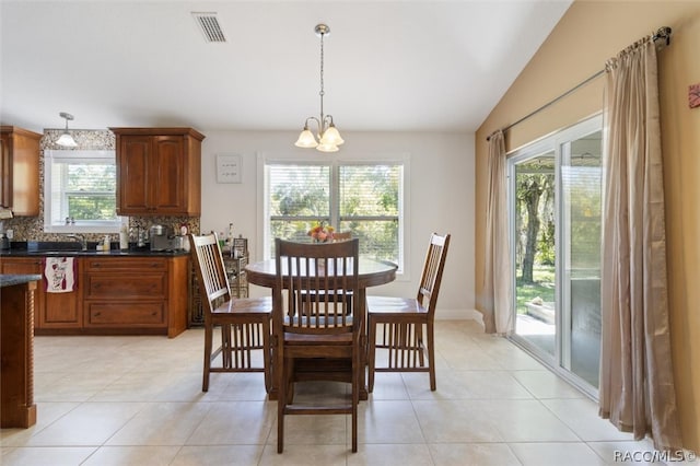 tiled dining room featuring a healthy amount of sunlight, lofted ceiling, and an inviting chandelier