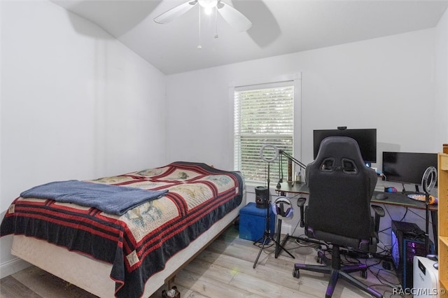 bedroom with ceiling fan, hardwood / wood-style floors, and vaulted ceiling