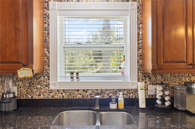 kitchen with decorative backsplash, a wealth of natural light, dark stone countertops, and sink