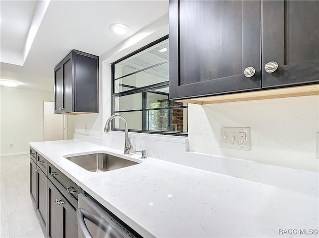 kitchen featuring light stone countertops, dishwashing machine, and sink