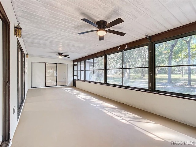 unfurnished sunroom featuring ceiling fan, plenty of natural light, and wooden ceiling