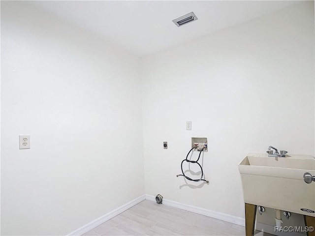 laundry area featuring hookup for a washing machine, electric dryer hookup, sink, and light hardwood / wood-style floors