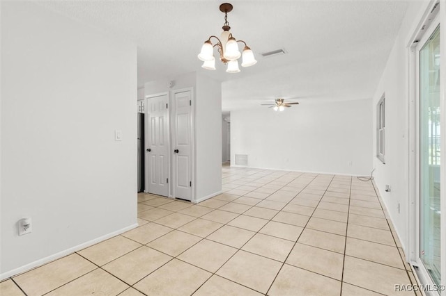 empty room featuring light tile patterned flooring and ceiling fan with notable chandelier