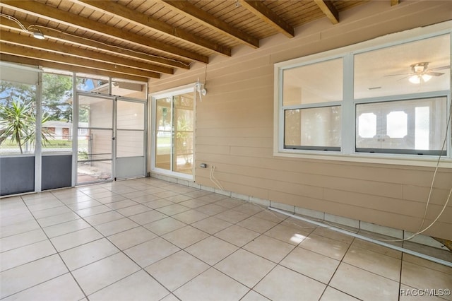 tiled empty room featuring beamed ceiling, wooden ceiling, wooden walls, and ceiling fan