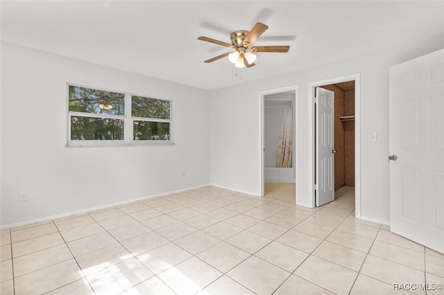 unfurnished bedroom with ceiling fan, a walk in closet, a closet, and light tile patterned floors