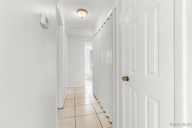 hall with a textured ceiling and light tile patterned flooring