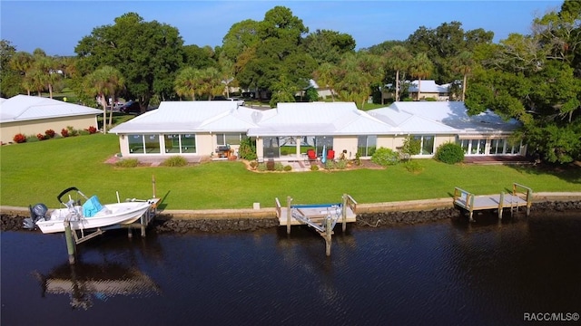 rear view of property featuring a water view and a lawn